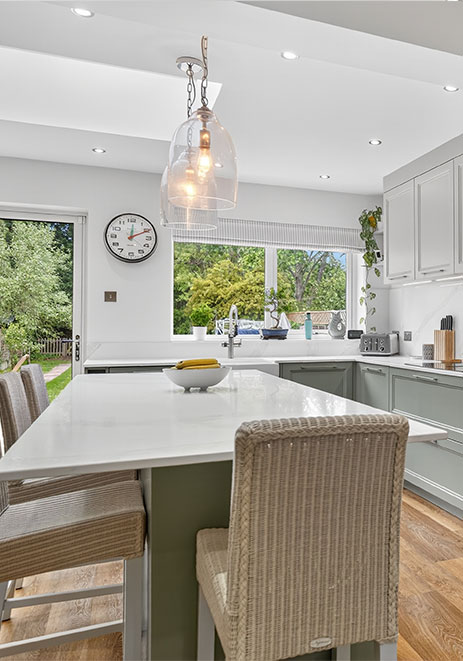 Sage green shaker kitchen island with breakfast bar seating and pendant lighting